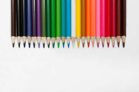 set of colored pencils arranged in a row horizontally on a white backgroundの写真素材
