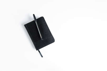 Notebook diary and pen in black on a white background top viewの写真素材