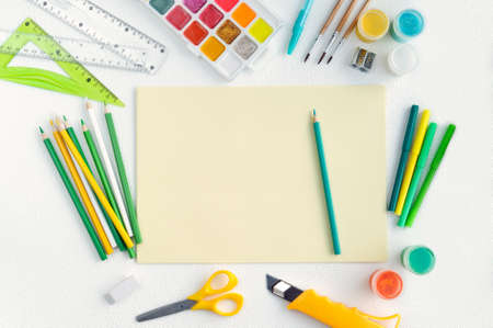 Blank yellow sheet of paper with colored school suppliesの写真素材