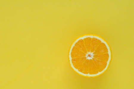 Slice orange fruit isolated on yellow color background for summer time with space for text.の写真素材