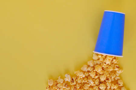 Sweet Caramel Popcorn in blue paper bucket isolated on yellow background with space for text.