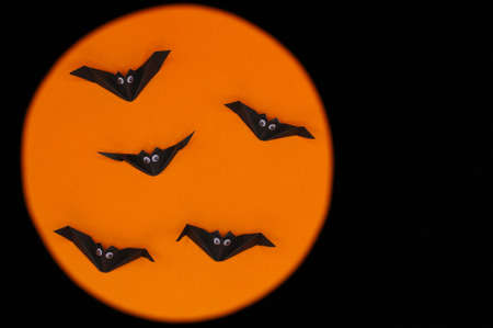 The Halloween origami (or Paper folding) of bats isolated on orange and black background with space...