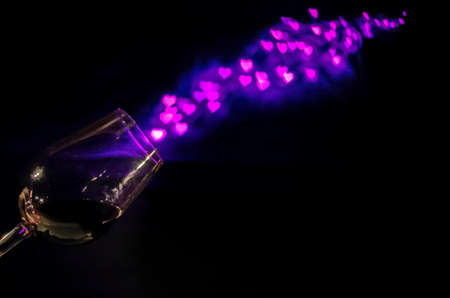 A glass of Red wine on black background with the line of love shape bokeh that splash out from the...
