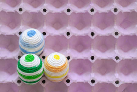 Colorful eggs decorate with knitting wool for Easter day and festival put in purple egg tray that...