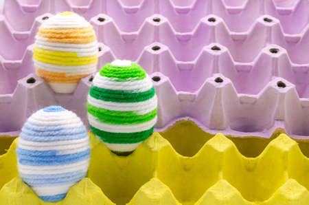 Colorful eggs decorate with knitting wool for Easter day and festival put in purple and yellow egg...