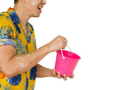 Asian Thai man with white clay filler on his face holding pink Bucket or Pail which is an accessory of water fighting for Songkran or Water festival in April which is summer & Thailand New Year.の写真素材