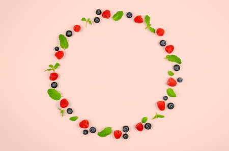 Fresh blueberries, raspberries and mint leaf on top view with pastel pink color background for healthy food concept.の写真素材