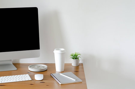 Modern personal computer screen on wooden table with a cup of coffee and Tillandsia air plant with...