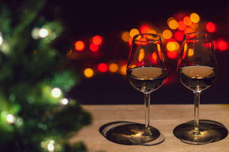 Two glasses of Rose wine on wooden table with Christmas tree and colorful bokeh light background.の写真素材