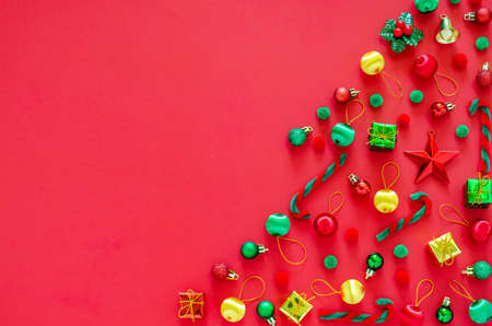 Christmas tree made of New yearâs ornament decorations on red background. Flat lay minimal Holiday concept.の写真素材