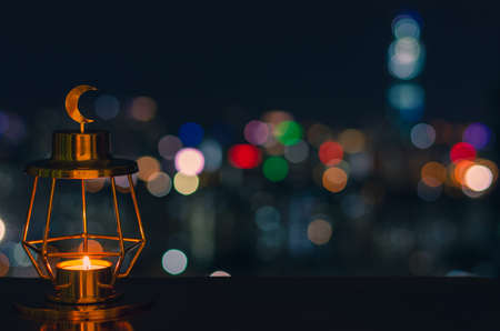 Modern golden lantern that have moon symbol on top with colorful city bokeh lights on dark background for the Muslim feast of the holy month of Ramadan Kareem.の写真素材