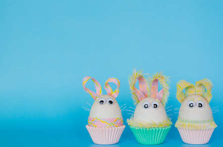 Easter eggs decorate as bunny dressing put on colorful cupcake paper cup with blue background. Cute...