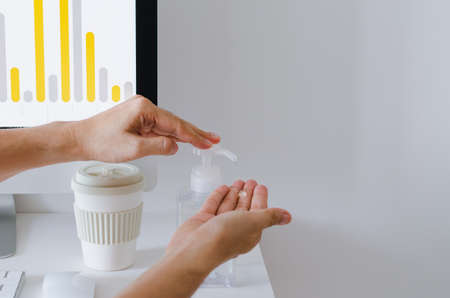Hand pumping alcohol gel from the bottle that put on working to clean and protect virus in the...