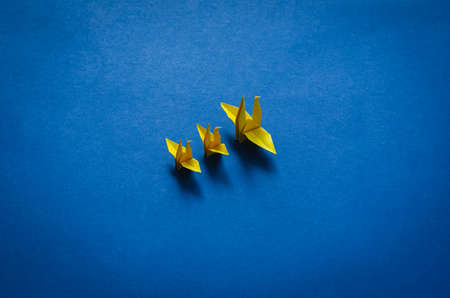 Yellow paper mother and baby birds on blue background. Minimal mother day concept.