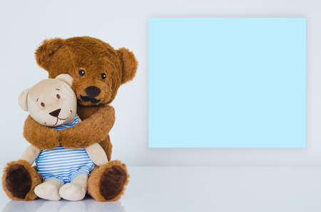 Father teddy bear with mustache hugging his son with empty blue space on white background. Father...