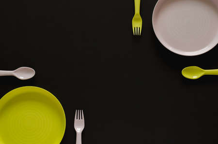 Colorful dish with fork and spoon put separate from each other on black background. New normal and...