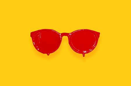 Red poster color painted on sunglasses with yellow background. Minimal summer concept.の写真素材