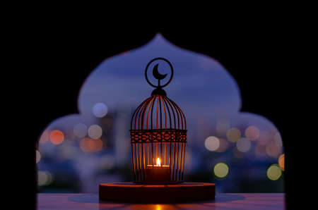 Lantern that have moon symbol on top with city bokeh light and blurred focus of paper cut for mosque shape background. Islamic new year concept.の写真素材
