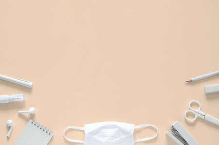 Flat lay of white mask with school and office stationery supplies for back to school and new normal...