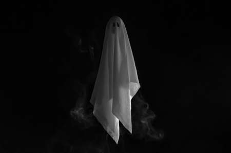 Partial focus of white ghost sheet flying in dark background with smoke. Halloween scary concept.