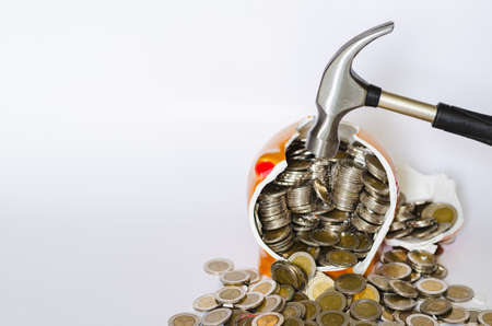 Hammer breaking piggy bank with Thai baht coins on white background