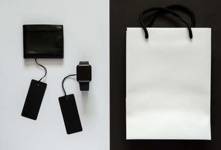Black price tags with merchandise and white shopping bag on white and black background. Black Friday concept.の写真素材