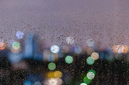 Rain drop on window with colorful bokeh lights.の写真素材