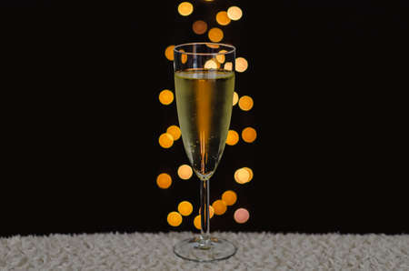 A glass of sparkling wine with bokeh lights on dark