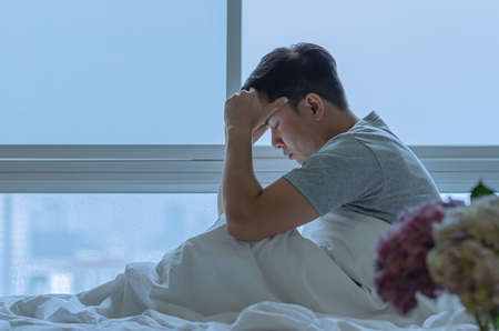 A person sitting and feeling depressed on bed. Depression and loneliness concept.