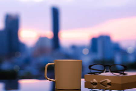 A cup of coffee with spectacles on book and ear pod put on table with city background and dawn sky. Stay home concept.の写真素材