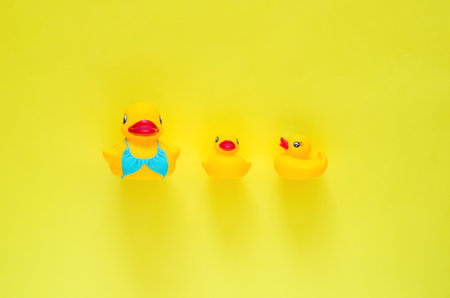 Rubber duck wearing blue swimming suit with her babies on yellow background. Minimal mother day and summer concept.の写真素材
