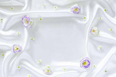Smooth elegant wavy white satin cloth texture background with flowers and space for text. Abstract,...