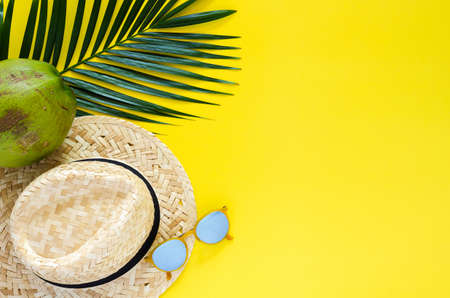 Beach hat, sunglasses and coconut fruit and leaves on yellow background. Summer concept.の写真素材