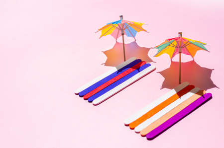 Colorful beach towels with sun umbrellas on pink sand beach. Minimal summer concept.