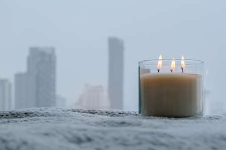 Flames burning at blurred aroma candle puts near by window in winter season. Zen and relax concept.の写真素材