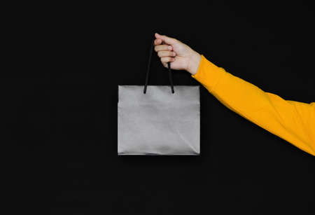 Hand holding black shopping bag on dark background. Black Friday concept.の写真素材