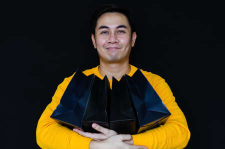 Asian male holding black shopping bags for Black Friday concept.の写真素材