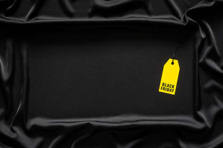 Yellow price tag with word on black cloth background. Black Friday concept.の写真素材