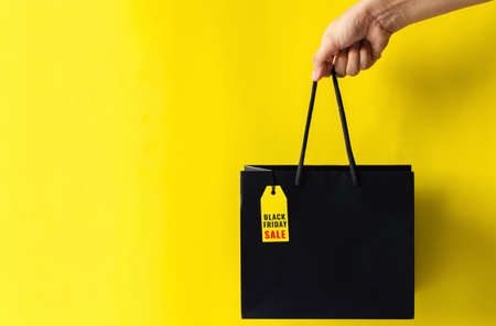 Hand holding shopping bag that have price tag with word for Black Friday shopping concept.の写真素材