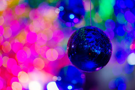 Blue bauble hanging to decorate for Christmas holiday with colorful bokeh from light and other baubles.の写真素材