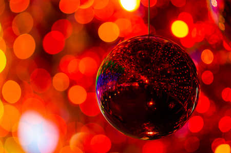 Red bauble hanging to decorate for Christmas holiday with colorful bokeh from light and other baubles.の写真素材
