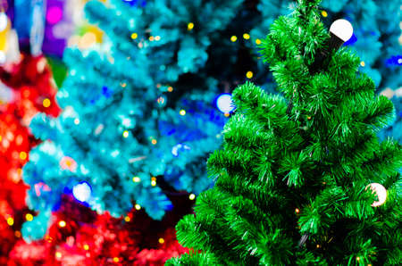 Green Christmas tree with light bulb and blurred focus of colorful Christmas trees.の写真素材
