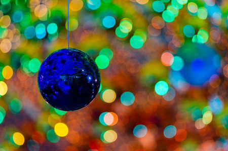 Blue bauble hanging to decorate for Christmas holiday with colorful bokeh from light and other baubles.の写真素材