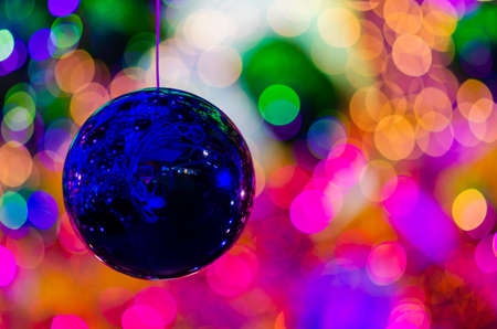 Blue bauble hanging to decorate for Christmas holiday with colorful bokeh from light and other baubles.の写真素材