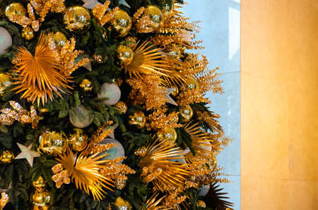 Golden and silver color baubles, ornaments and dry leaves decorated on big Christmas tree.の写真素材