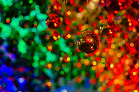 Golden bauble hanging to decorate for Christmas holiday with colorful bokeh from light and other...