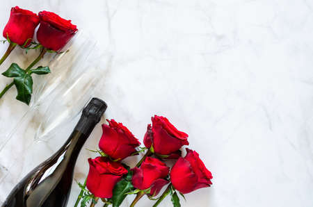 Champagne bottle with two glasses and red roses on marble background for anniversary and Valentine's day concept.の写真素材