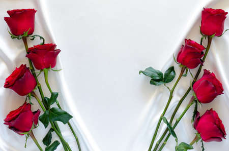 Red roses put on white satin cloth background for anniversary, mother and Valentine's day concept.