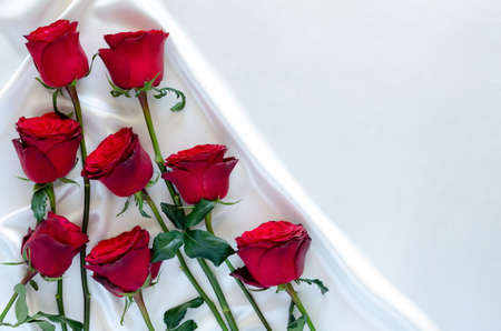 Red roses put on white satin cloth background for anniversary, mother and Valentine's day concept.の写真素材