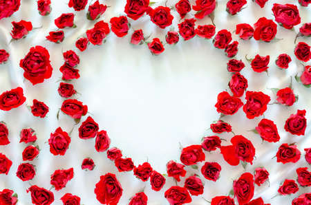 Red roses put on white satin cloth with empty space of love shape background for anniversary and Valentine's day concept.の写真素材